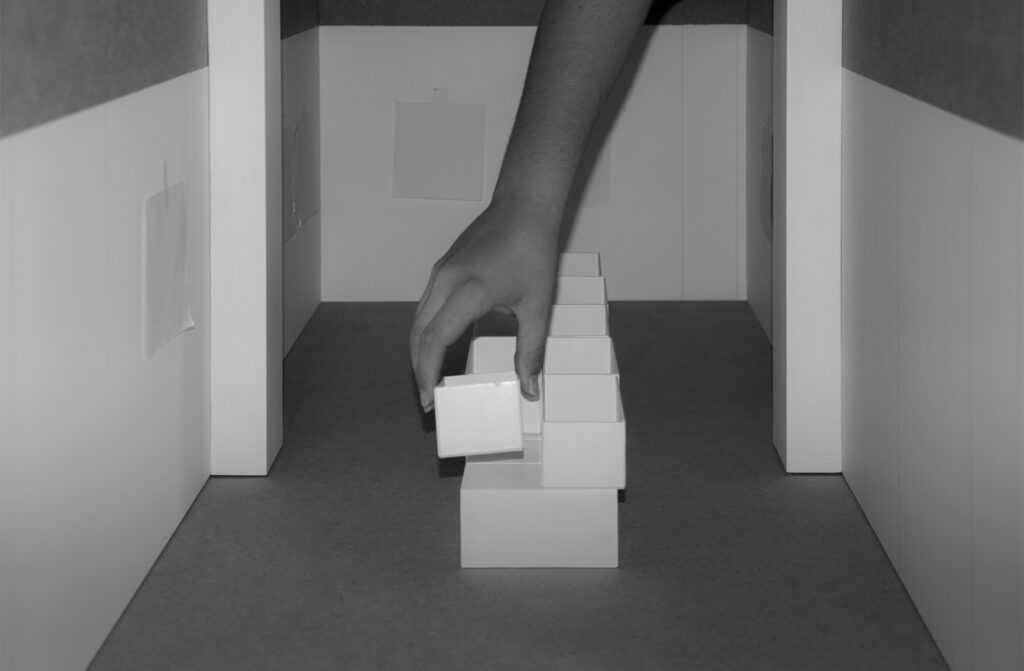 Fotografia che ritrae una mano che posa un cubo di cartone sopra altri cubi